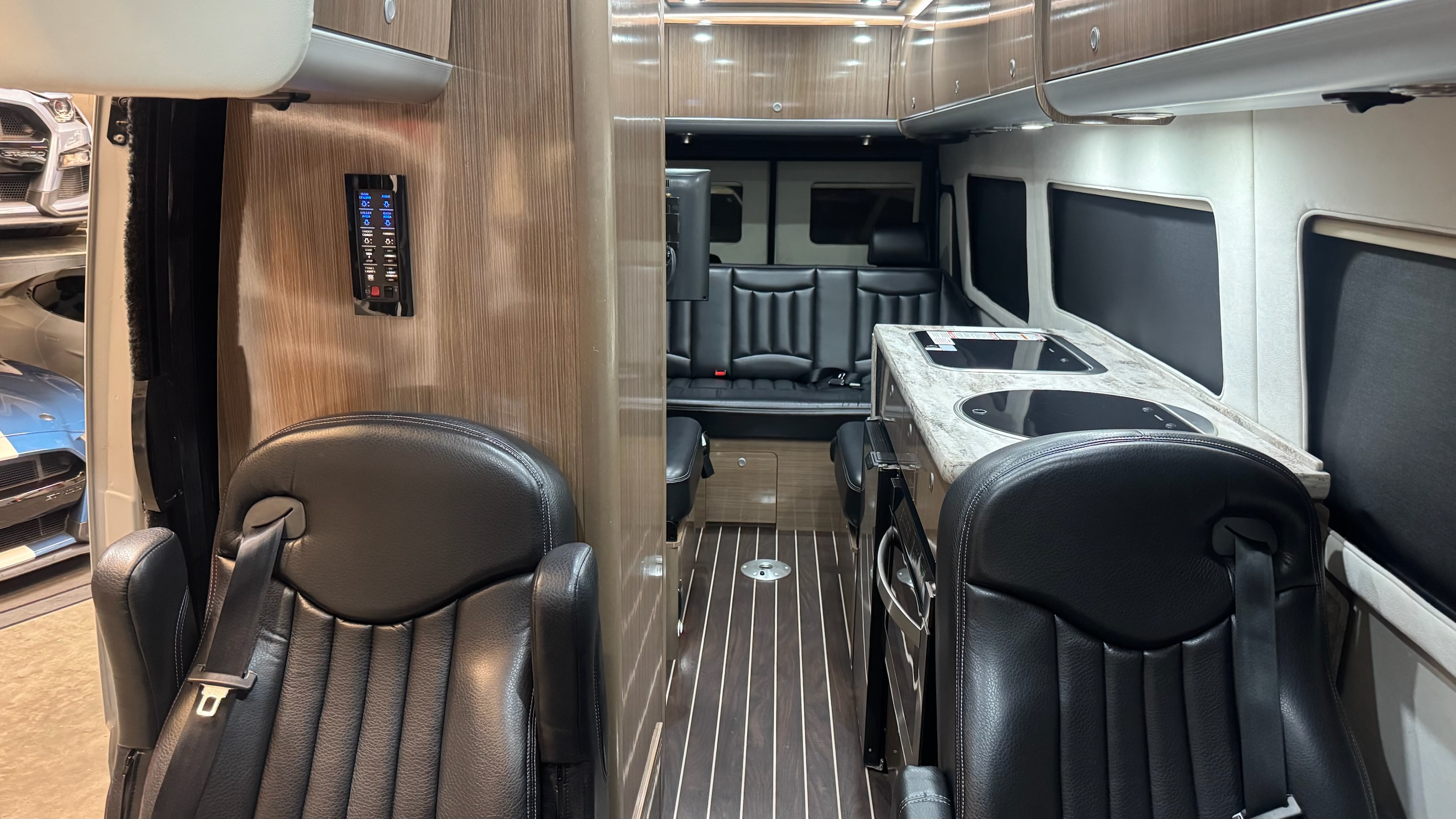 Full cabin interior — captain's chairs, teak floor, kitchen